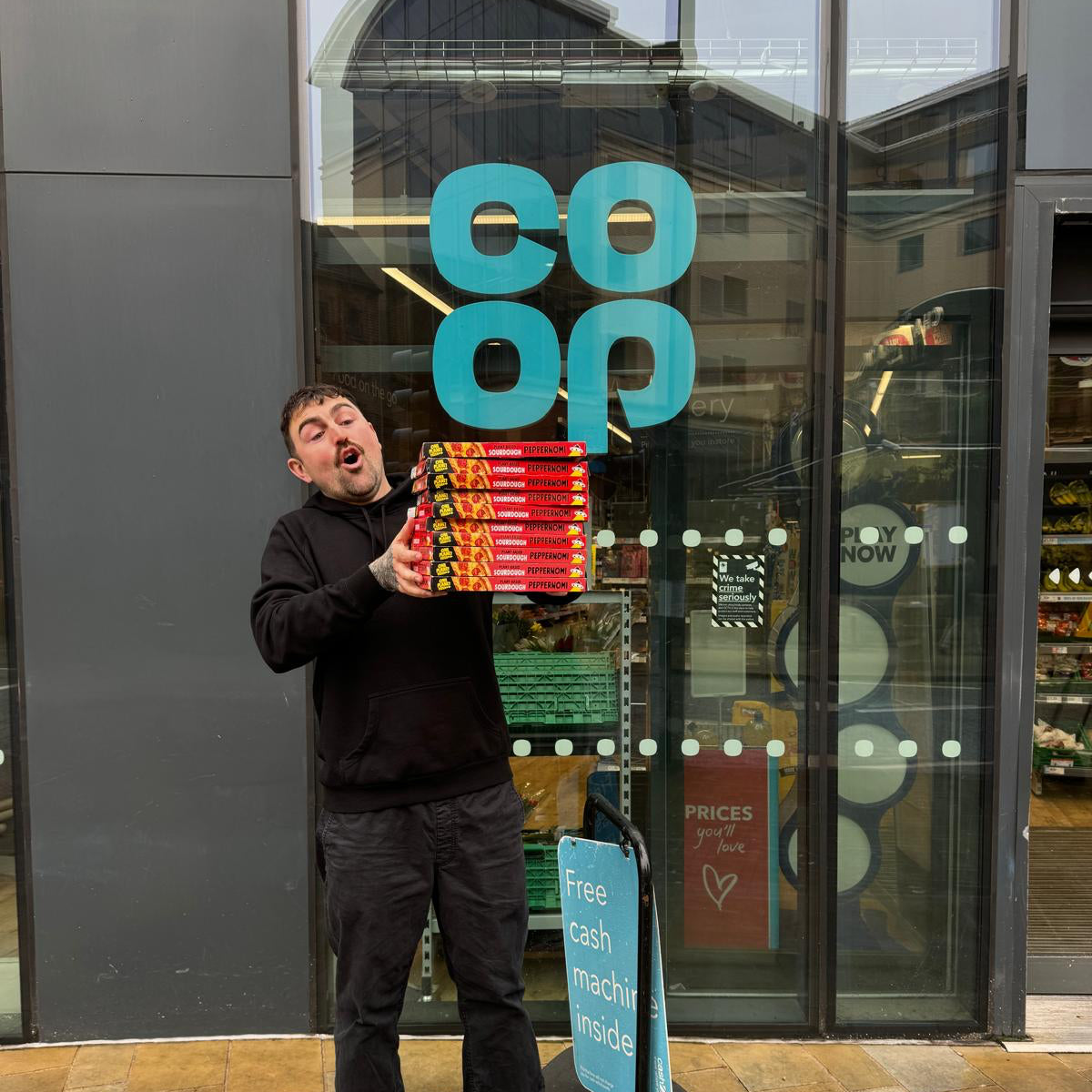 Person holding colorful boxes in front of a Co-op store entrance